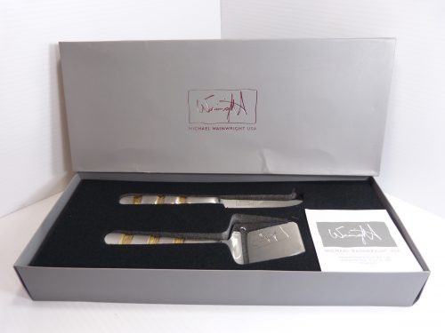 Michael Wainwright Giotto Gold Cheese Shaver & Knife Set. The utensil set is in excellent used condition with little signs of use. The box is a little creased and rubbed. Please check photos carefully.